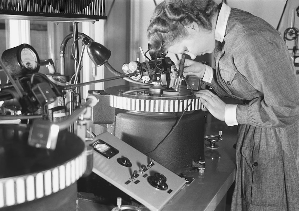 une femme regardant à travers un microscope dans une pièce