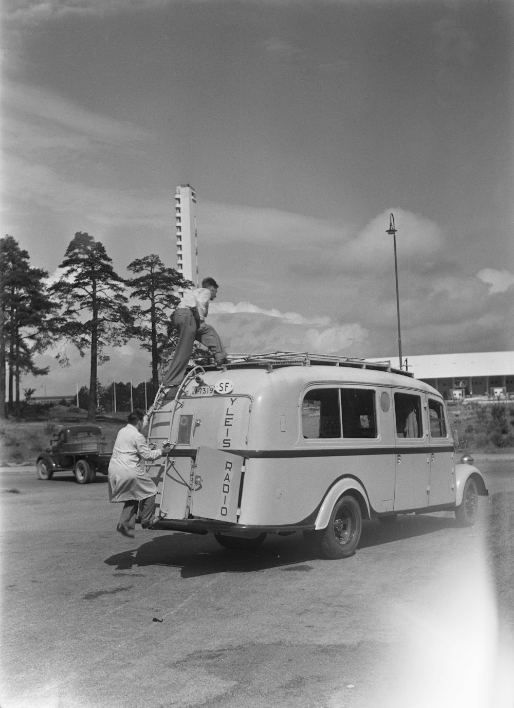 a black and white photo of a man standing on top of a van