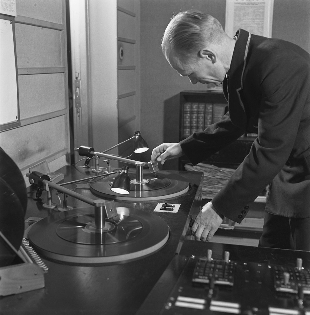 a man standing over a record player in a room