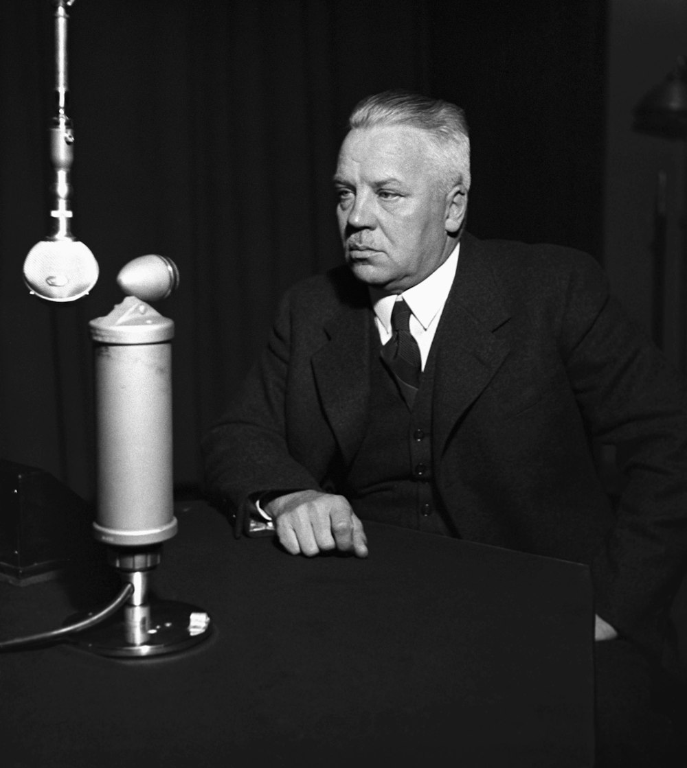 a man sitting at a table with a microphone in front of him