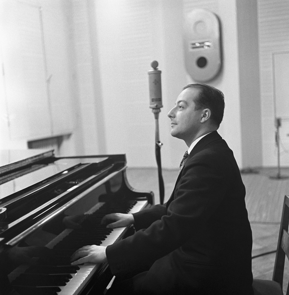 a man in a suit sitting at a piano