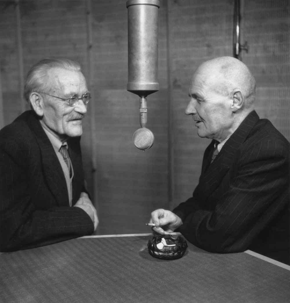 a couple of men sitting at a table next to each other