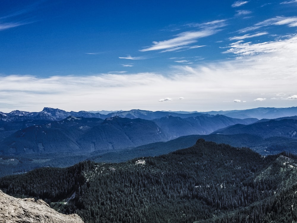 a man sitting on top of a mountain with a view of the mountains