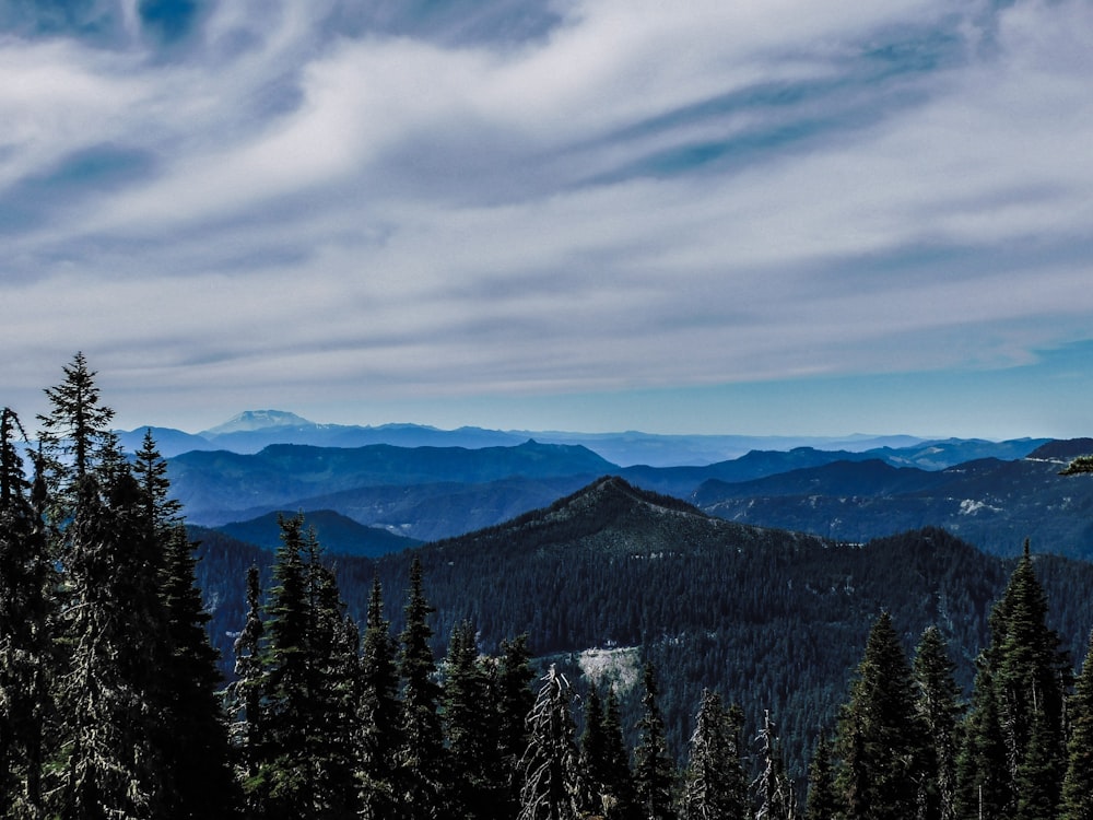 a view of a mountain range with trees and mountains in the background