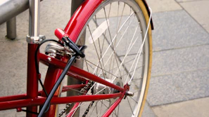 A close-up of a bright red security disc lock attached to a motorcycle wheel, highlighting its solid build.