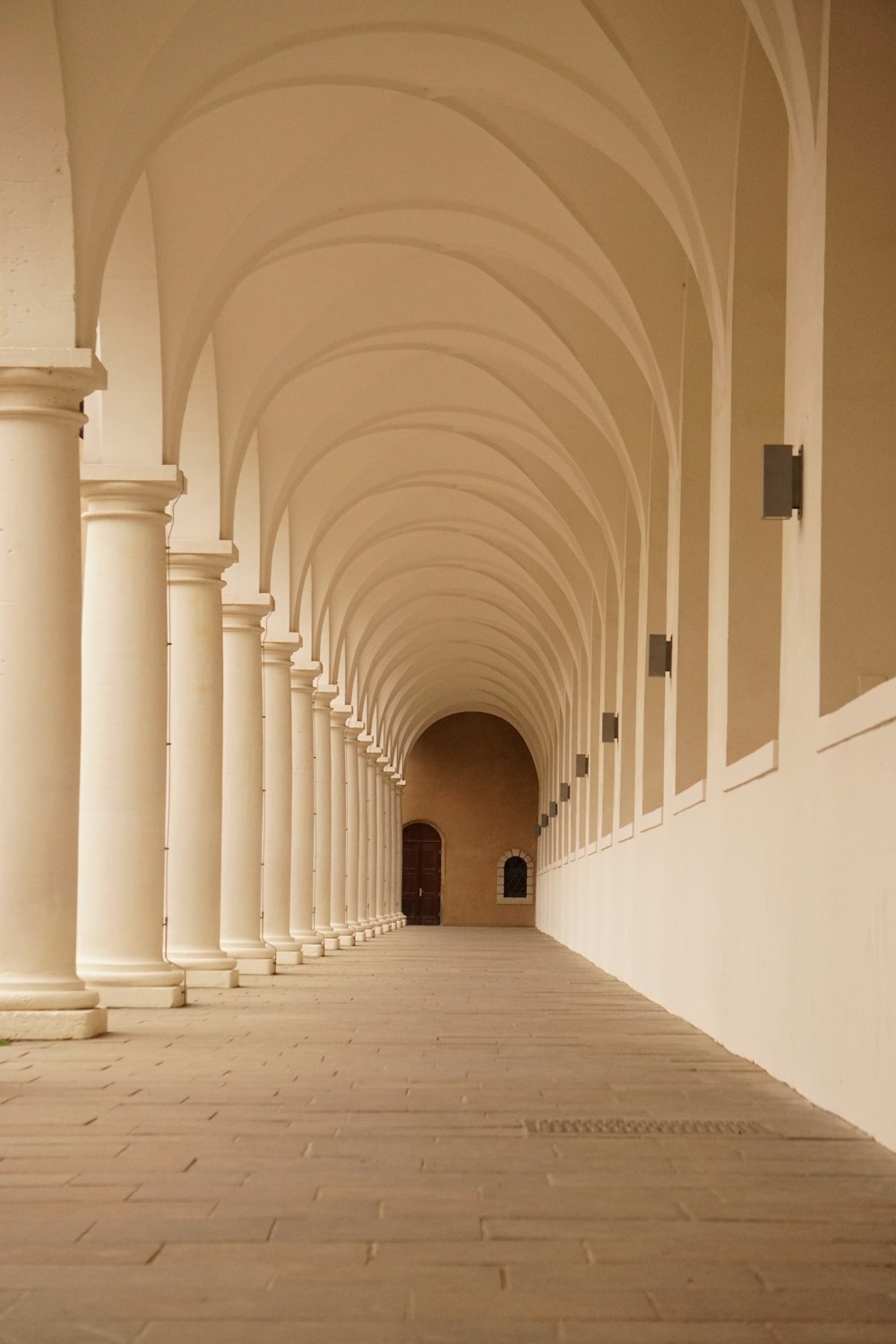 a long hallway with columns and a clock on the wall