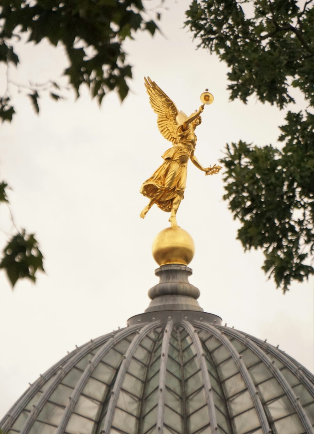 une statue dorée au sommet d’un bâtiment en forme de dôme