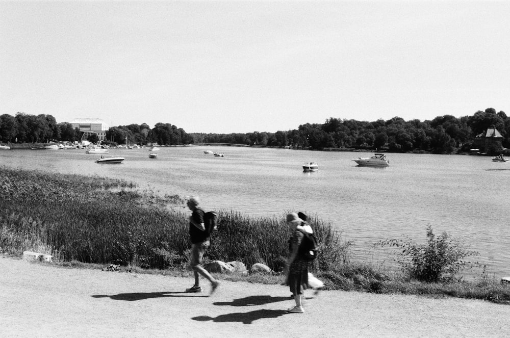 a couple of people that are walking by some water