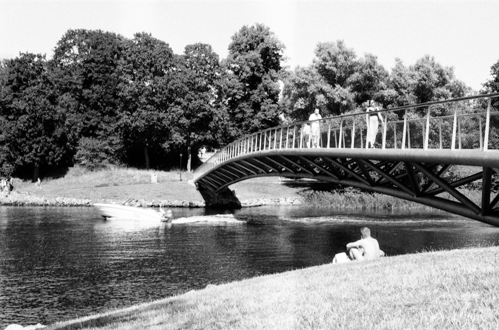 a black and white photo of people walking across a bridge