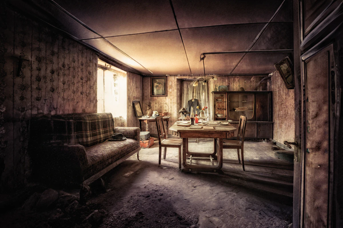 An old, dusty living room with a couch, a table and chairs