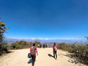 Pilgrims walking along a mountain trail towards Badrinath under a clear blue sky