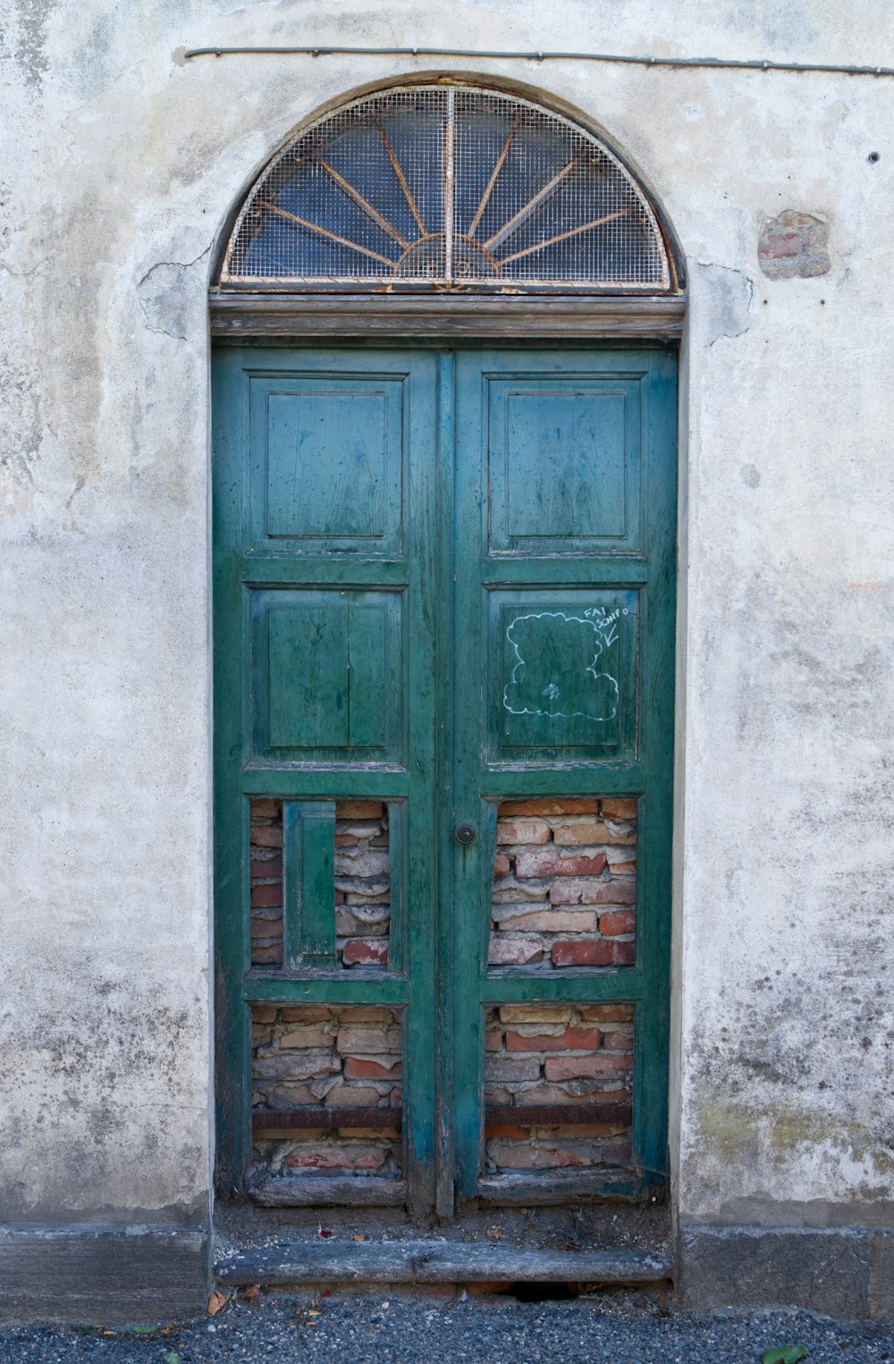 Una puerta verde con una pared de ladrillo detrás