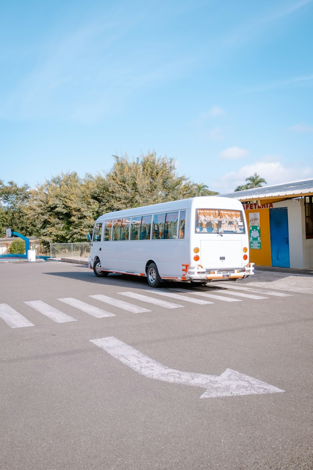 a white bus parked in a parking lot next to a building