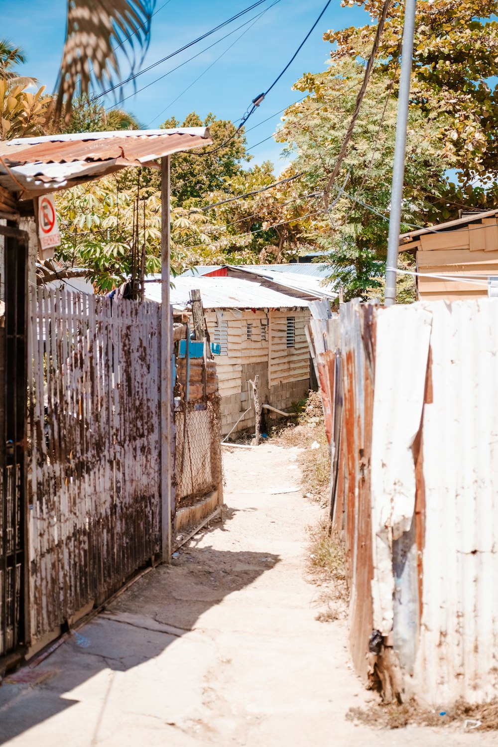 a dirt road with a fence and a shack