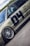 A detailed view of a customized car with prominent wheel rims and a matte finish. The car features decals and sponsor logos, highlighting brands such as BBS and Recaro, with a large number 04 on the side. The vehicle is positioned on a smooth road surface, with greenery visible in the background under a partly cloudy sky.