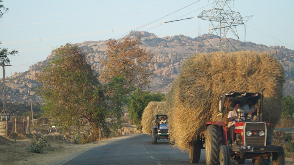 a tractor pulling a load of hay down a road