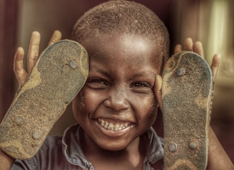 A child smiling brightly while receiving a new pair of durable shoes.