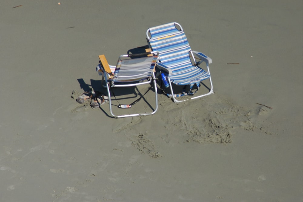 a couple of lawn chairs sitting on top of a sandy beach