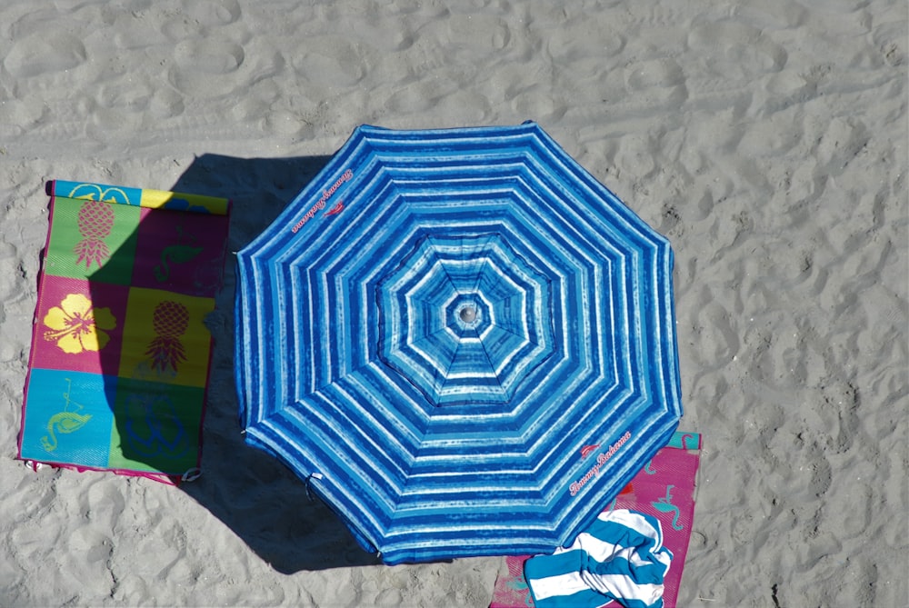 a blue umbrella sitting on top of a sandy beach