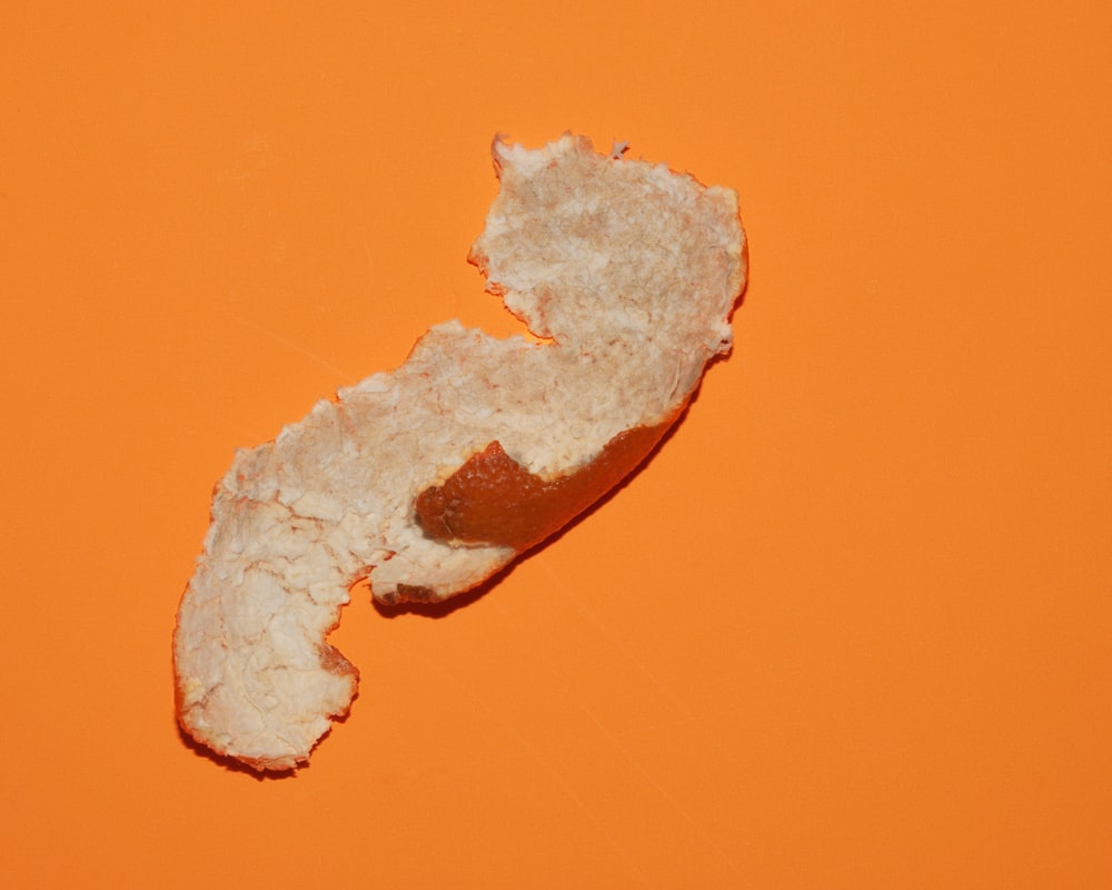 a half eaten piece of bread on an orange background