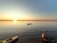 A serene lake at sunset with a lone kayak gliding smoothly over the water.
