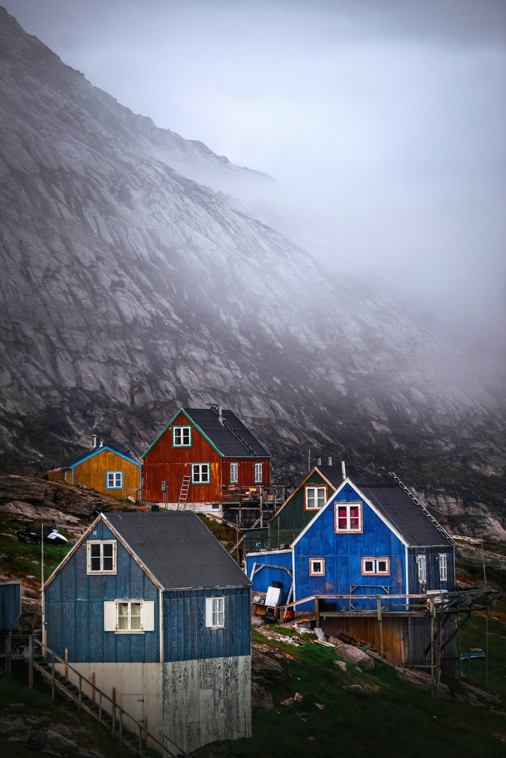 a group of houses sitting on top of a lush green hillside