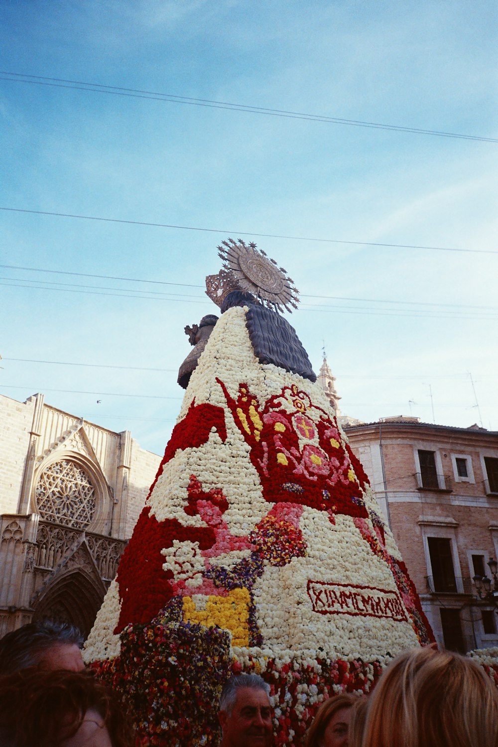 a large christmas tree made of flowers in front of a building