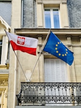two flags are flying in front of a building