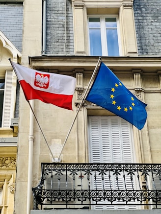 two flags are flying in front of a building