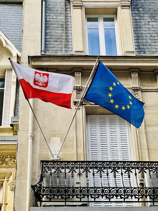 two flags are flying in front of a building