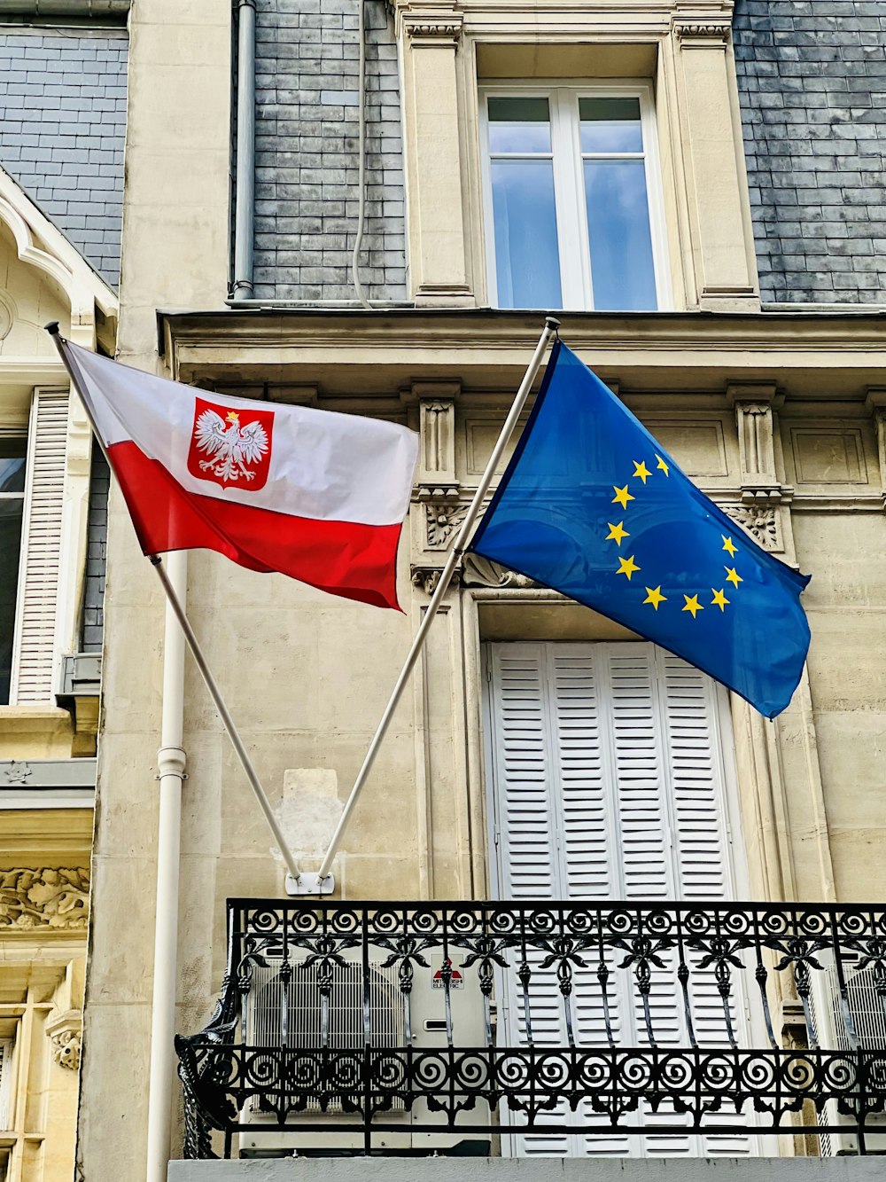 two flags are flying in front of a building