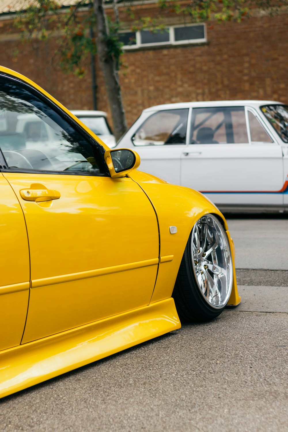 a yellow car parked in front of a white car