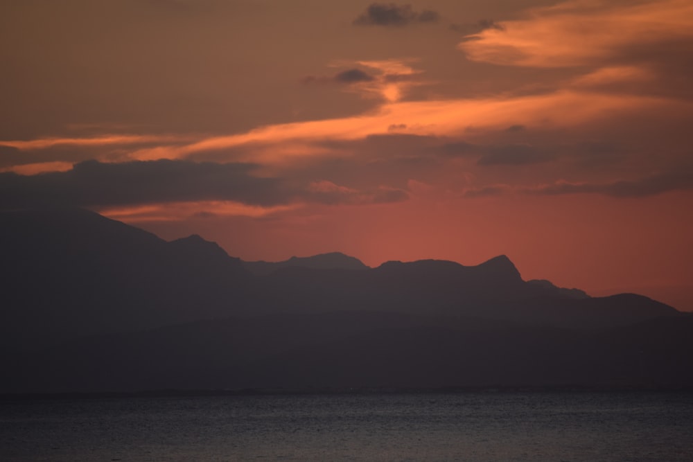 the sun is setting over a mountain range