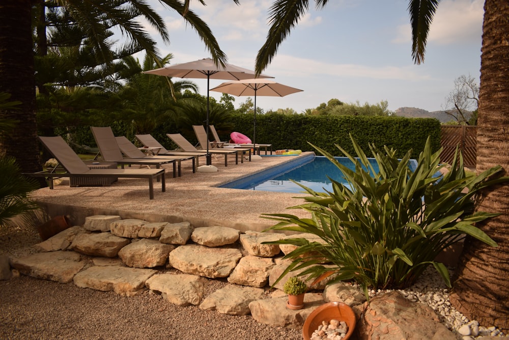 a pool with lounge chairs and umbrellas next to it