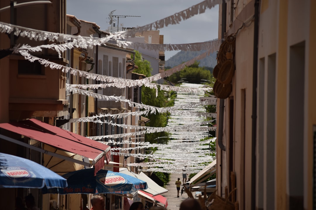 a narrow street lined with buildings and umbrellas,