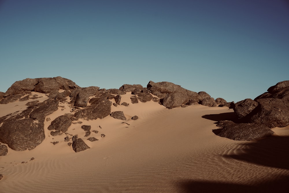 rocks and sand in the desert under a blue sky