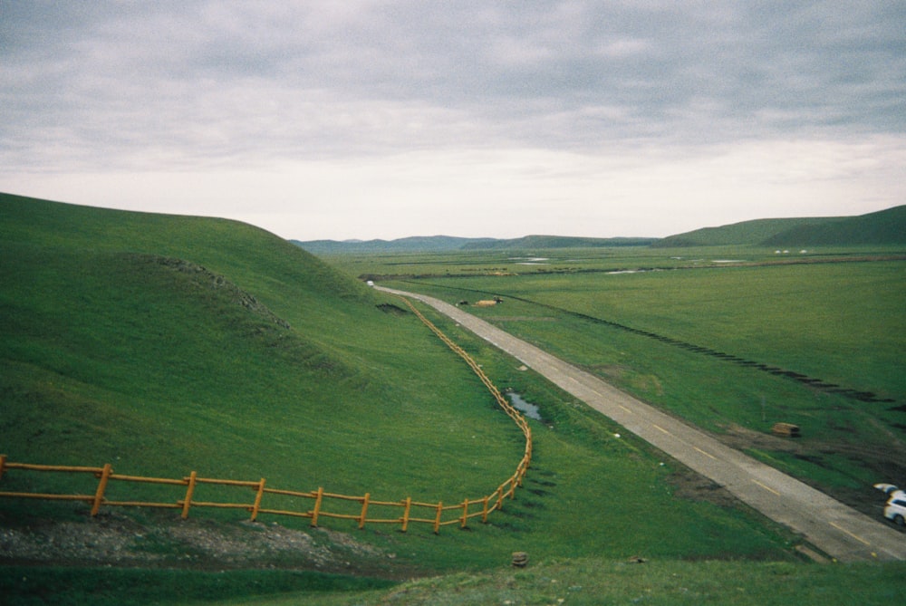 a truck driving down a road in the middle of a lush green field