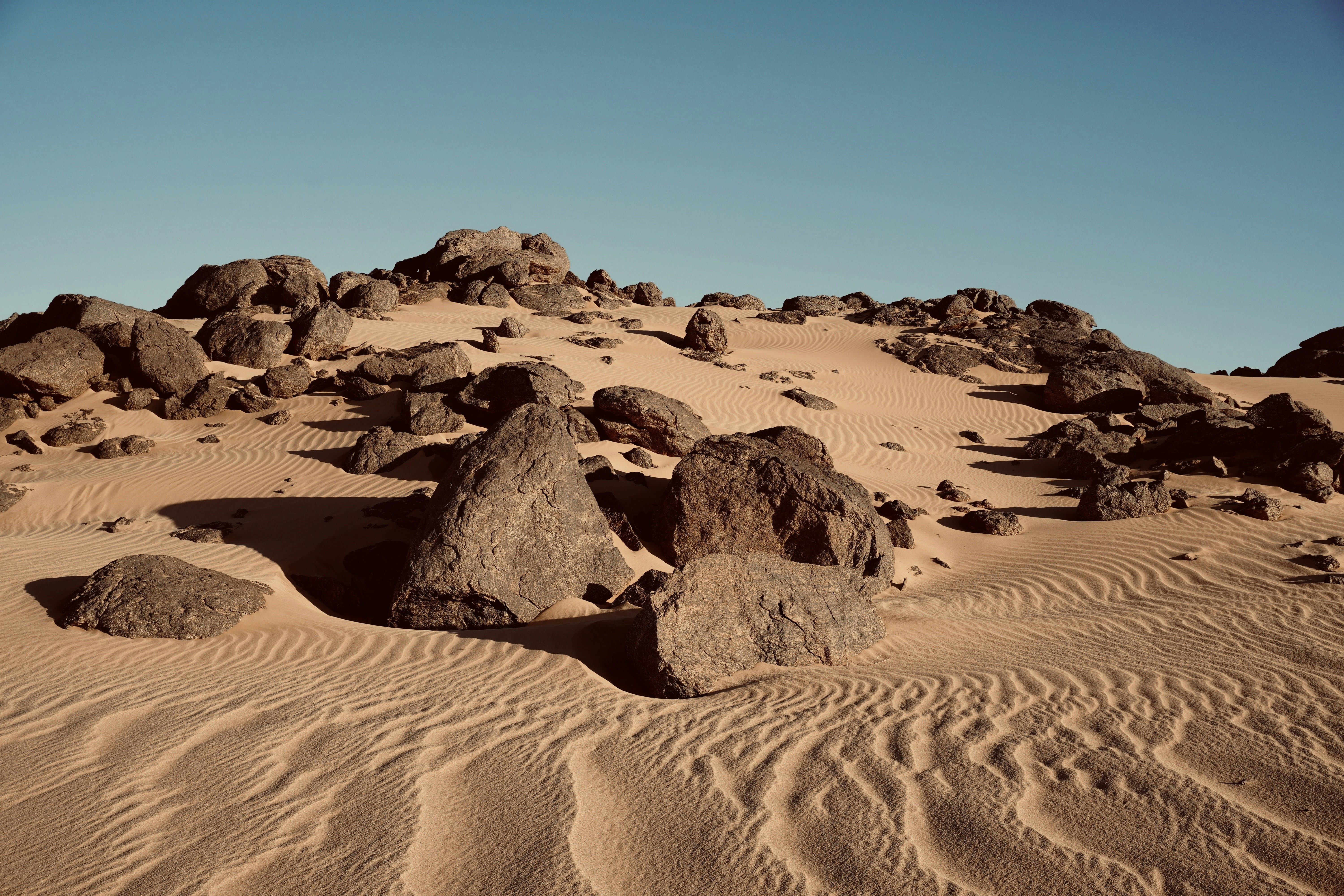 rocks and sand in the desert under a blue sky