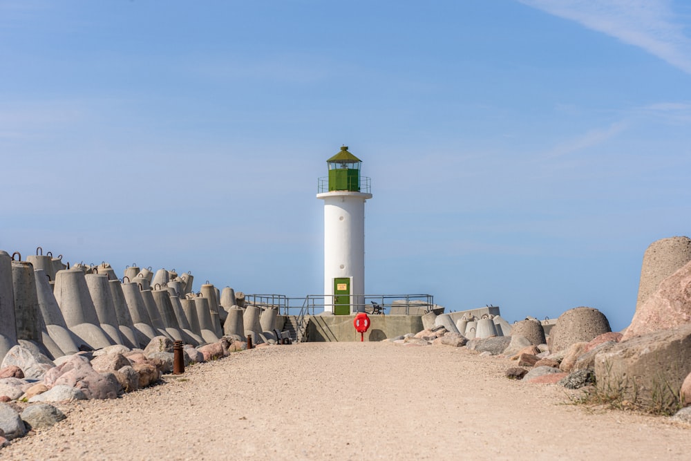 Ein weiß-grüner Leuchtturm auf einem Sandstrand