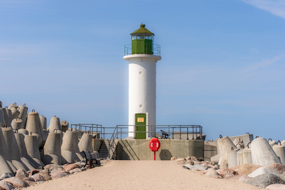 Ein weiß-grüner Leuchtturm auf einem Sandstrand