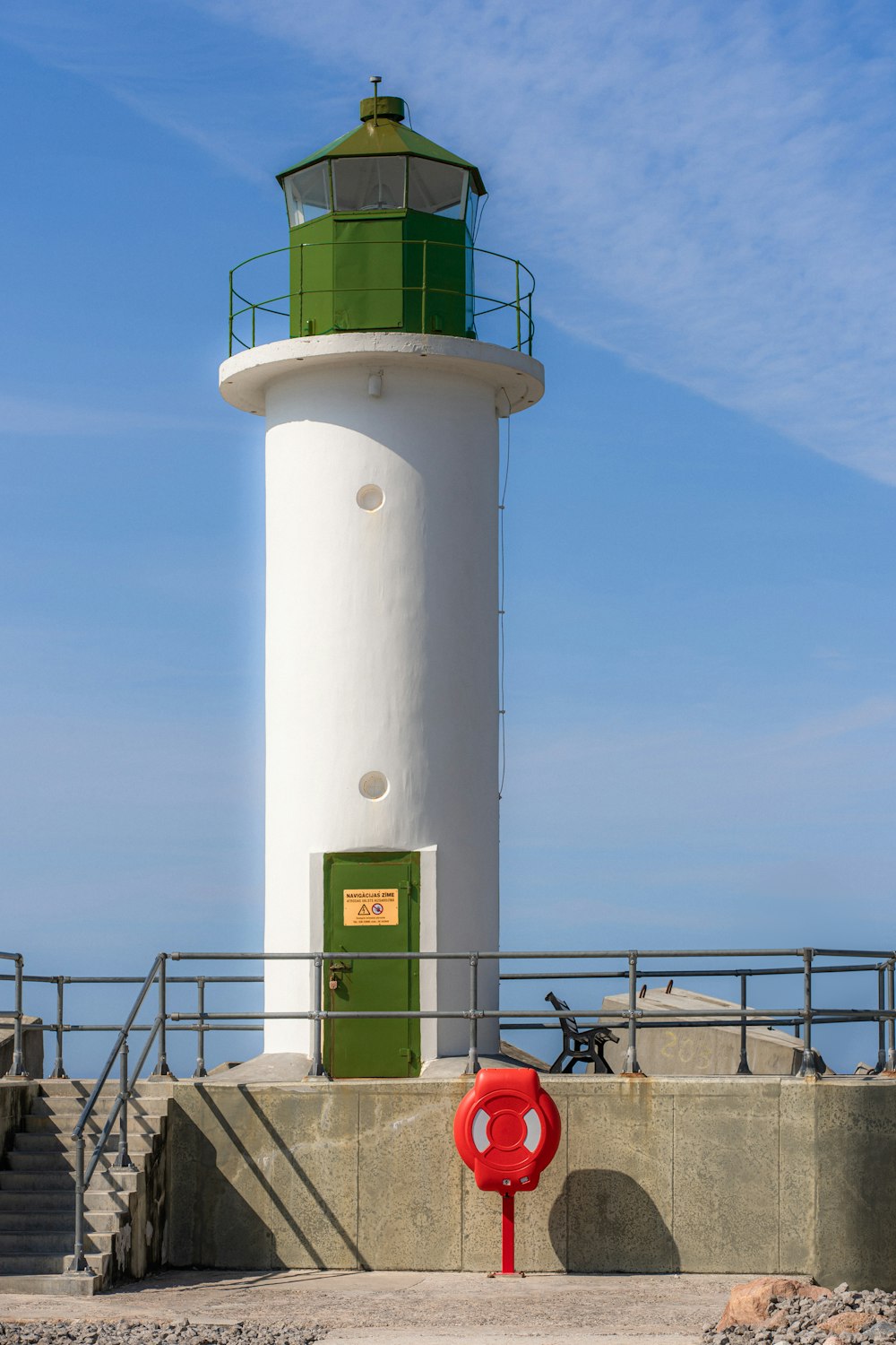 a white and green lighthouse with a red fire hydrant