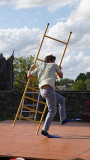 A person wearing safety shoes while working on a ladder outdoors.
