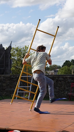 A person wearing safety shoes while working on a ladder outdoors.