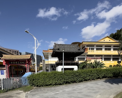 a yellow building with a black roof next to a street