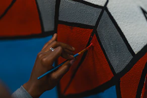 Close-up of a mural artist painting bold, colorful patterns on a large urban wall.