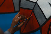 Close-up of hands painting a mural symbolizing community and creativity.