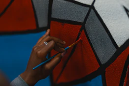 Close-up of hands painting a mural symbolizing community and creativity.