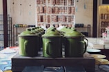 A set of enamel storage canisters lined up neatly on a wooden shelf.
