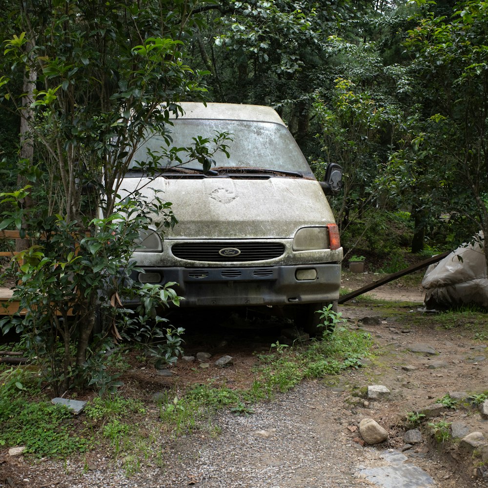 a van parked in a wooded area next to a tree