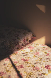 A sunlit bedroom featuring a floral bedding set with soft pastel colors and delicate patterns
